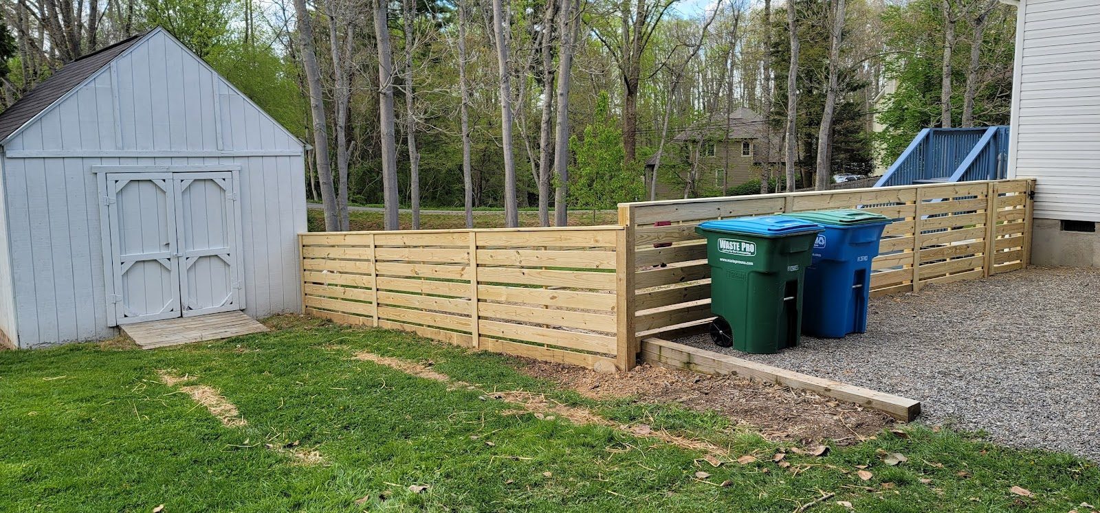Horizontal board wood fence around a shed and trash area