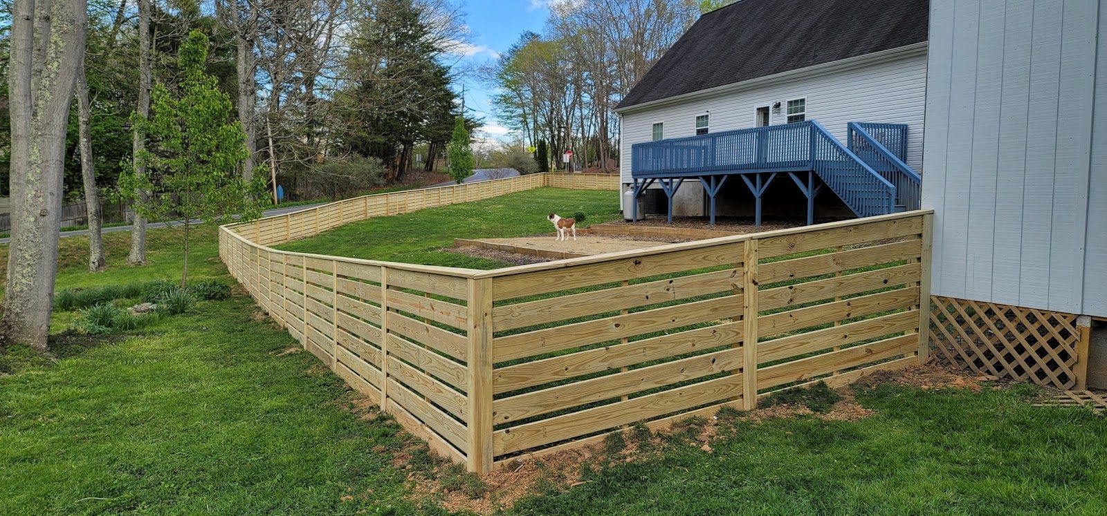 Horizontal board wood fence enclosing a yard beside a blue deck